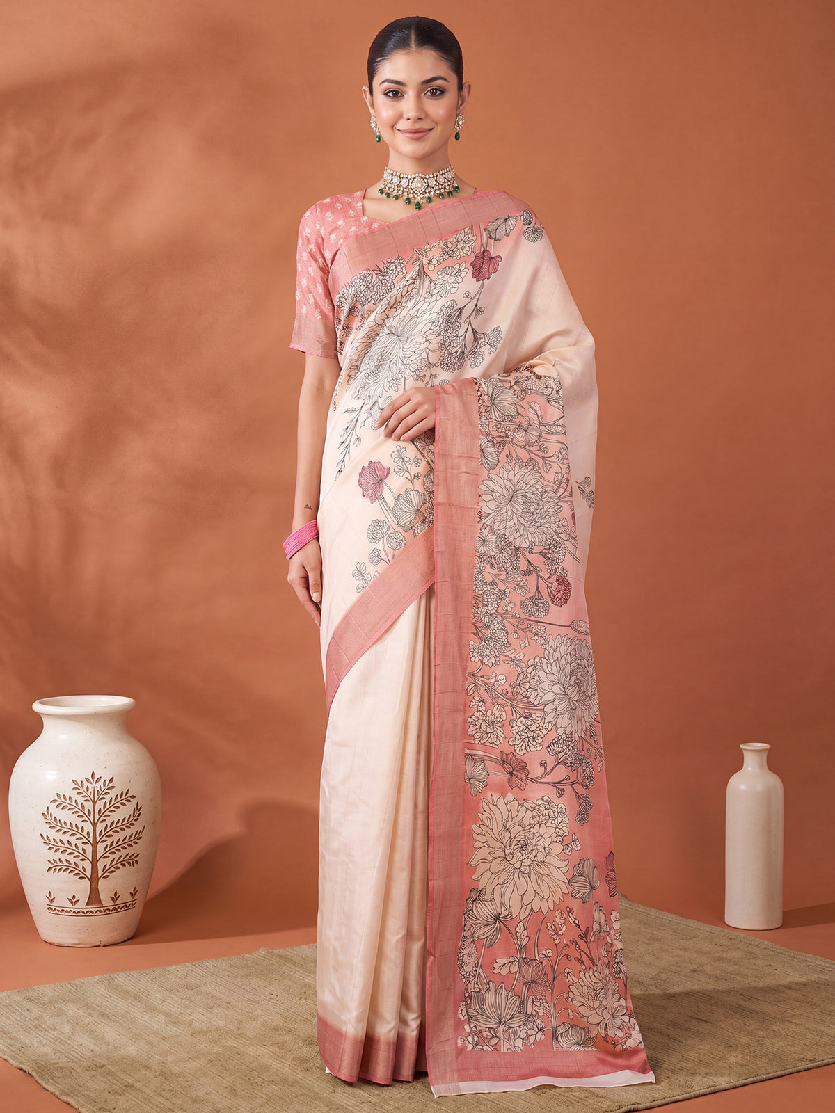 Woman wearing off white satin silk saree with all-over floral design and peach blouse