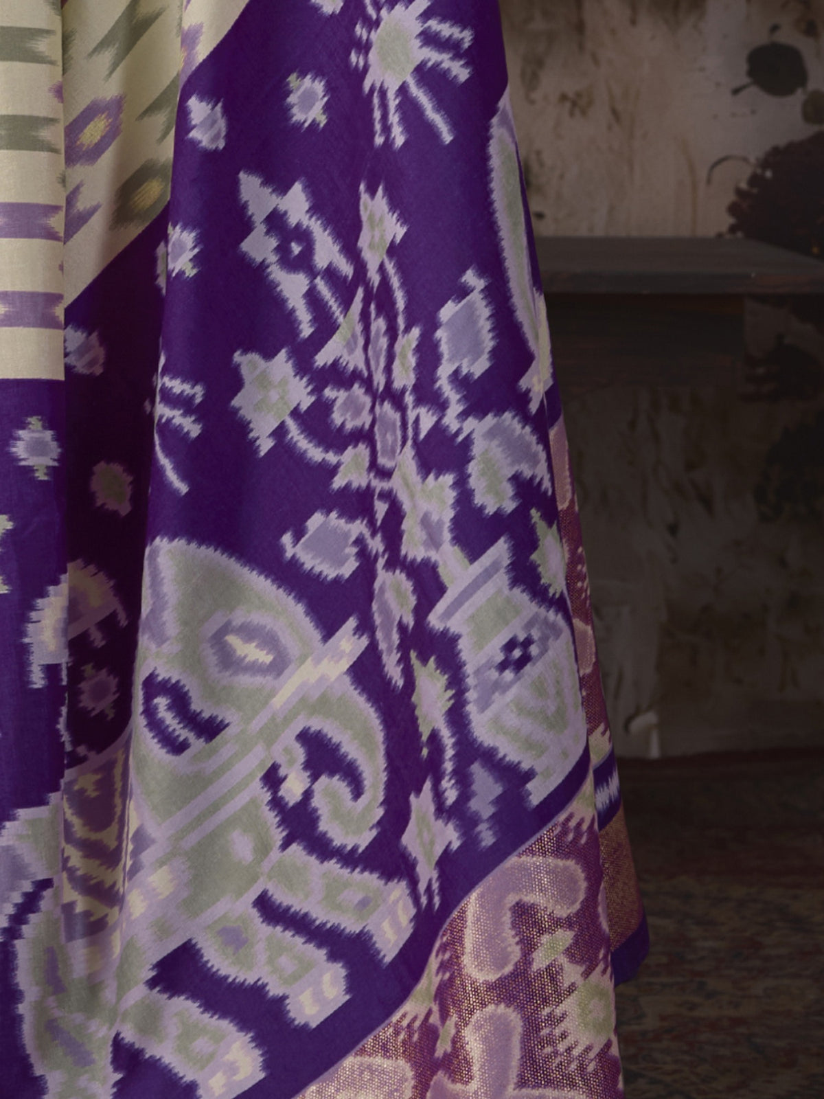 Pallu detail of off white silk blend saree showing ikat resist-dyed pattern and embellished border