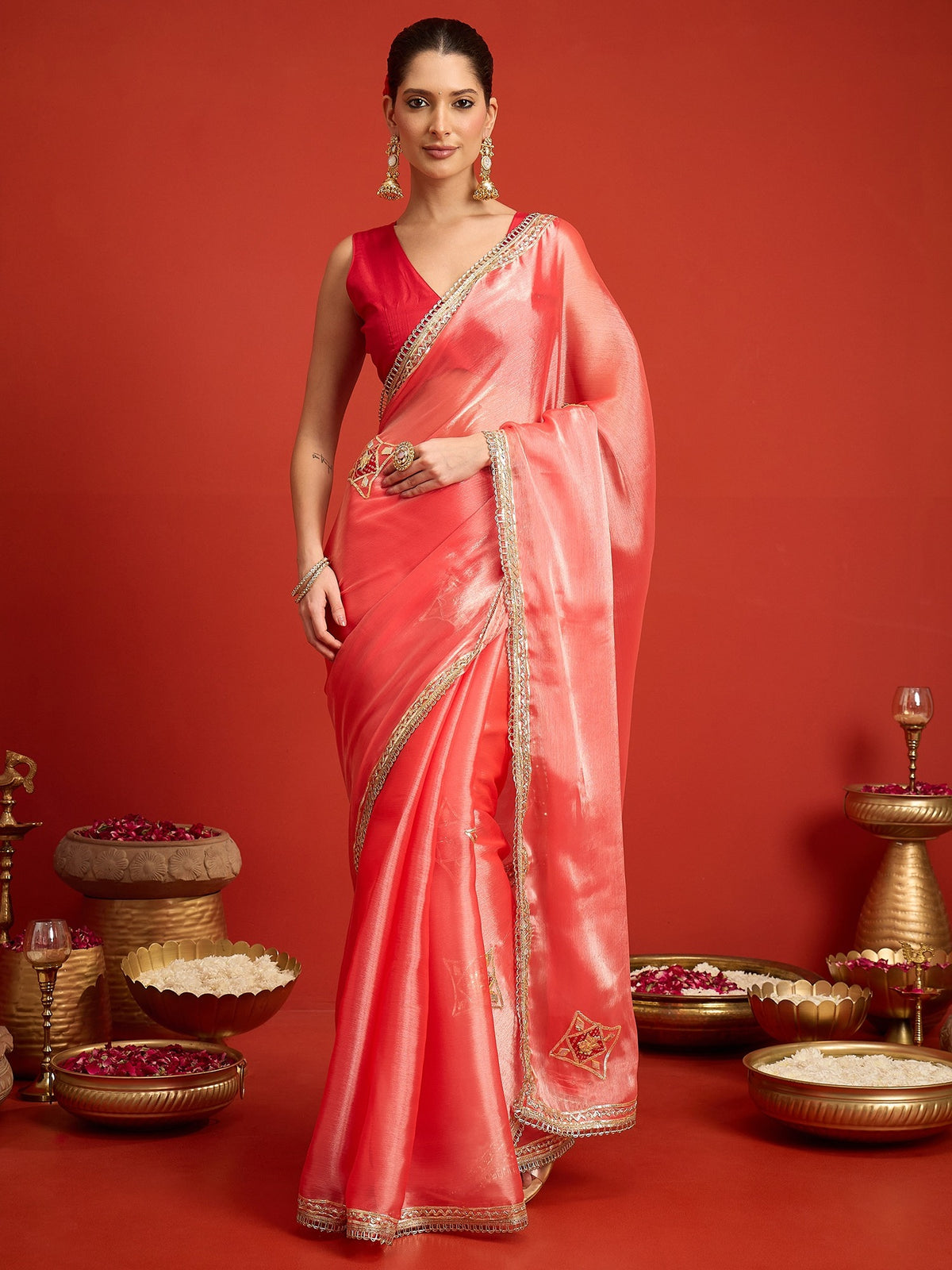 Woman wearing peach paper silk saree with ornamented surface design and coral blouse