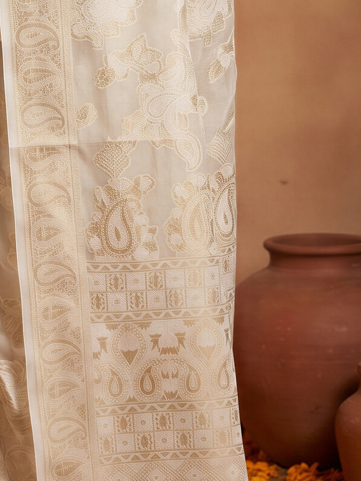 Pallu detail of white organza saree showing traditional indian motif work and zari border
