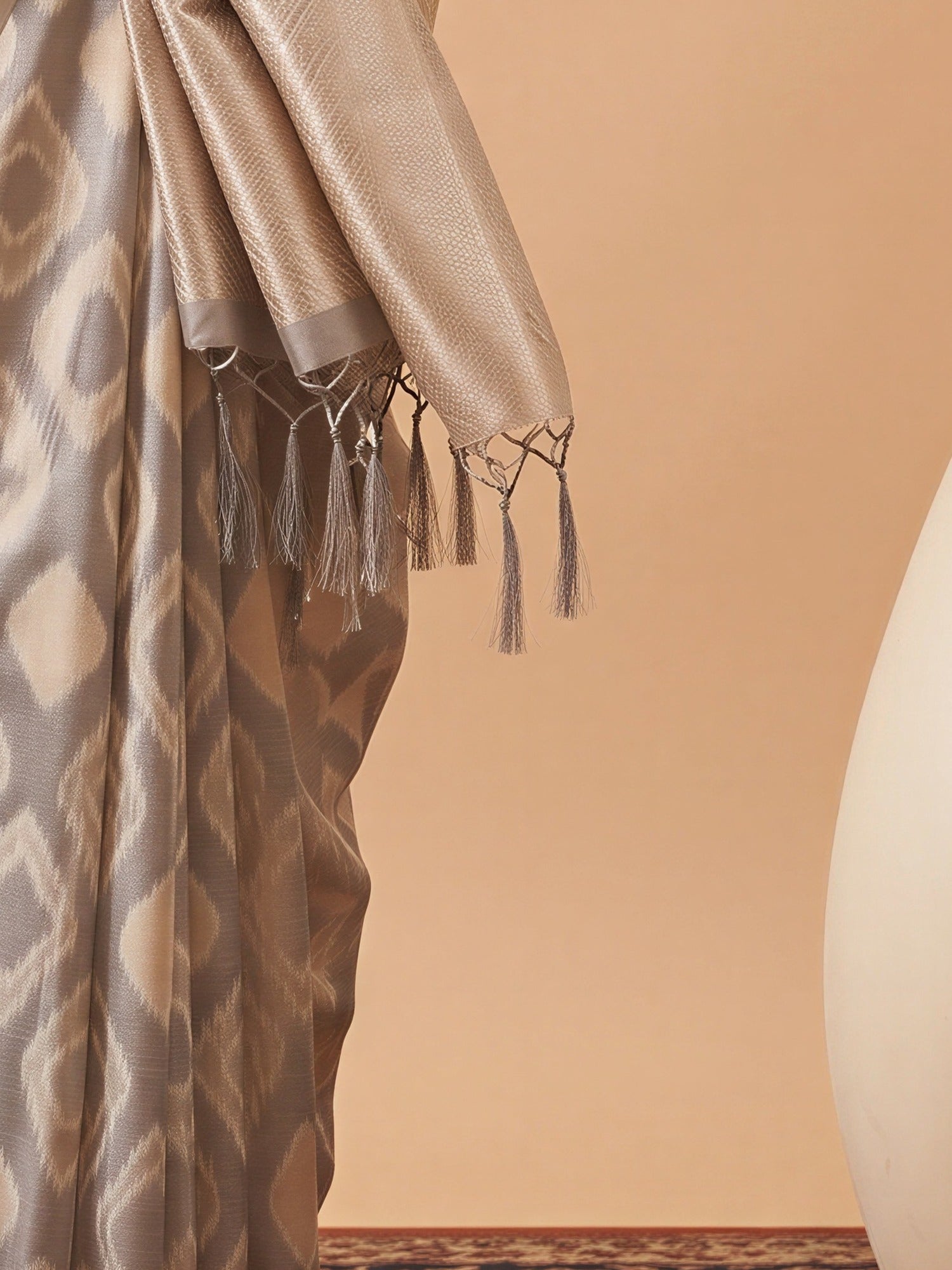 Pallu detail of beige tissue saree showing geometric pattern design and zari border