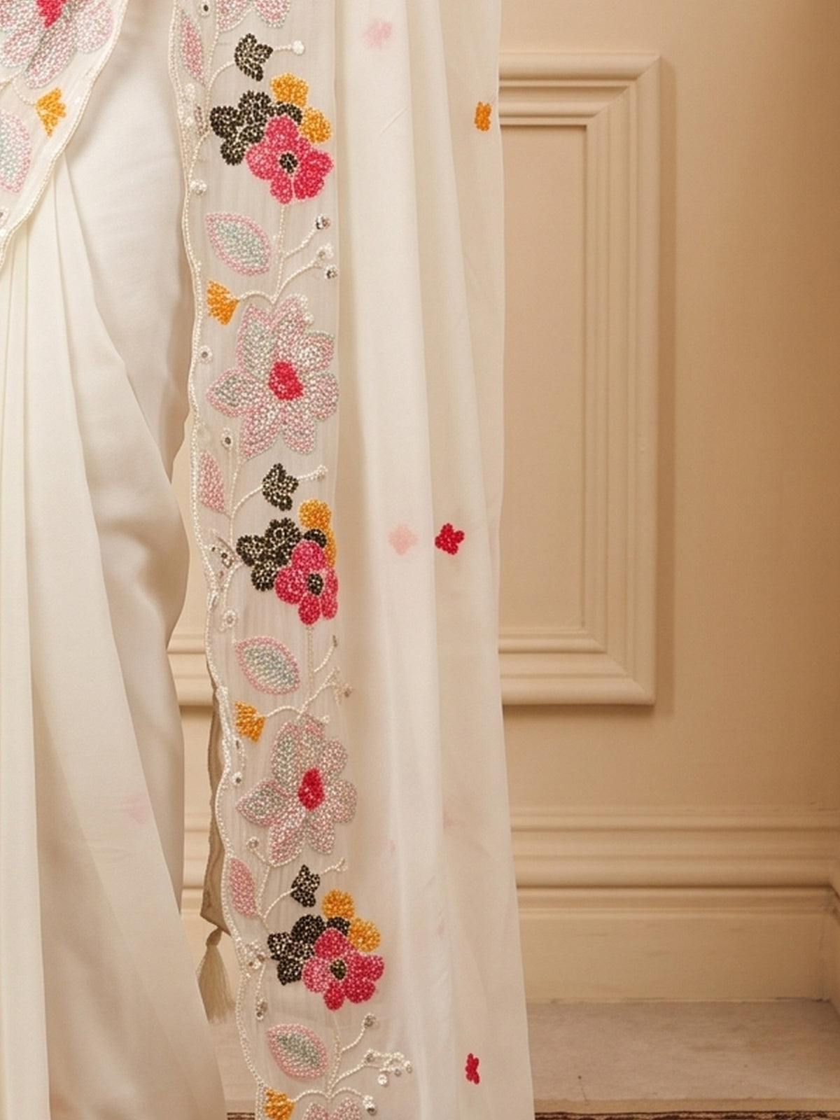 Pallu detail of white georgette saree showing embroidered motif work and embellished border