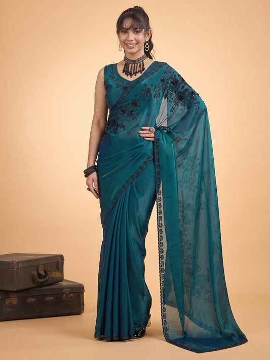Woman wearing teal green satin silk saree with ornamented surface design and teal green blouse