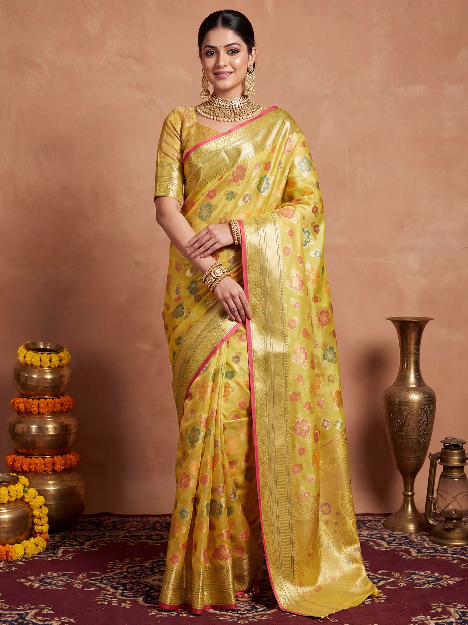 Woman wearing yellow organza saree with traditional indian motif work and yellow blouse