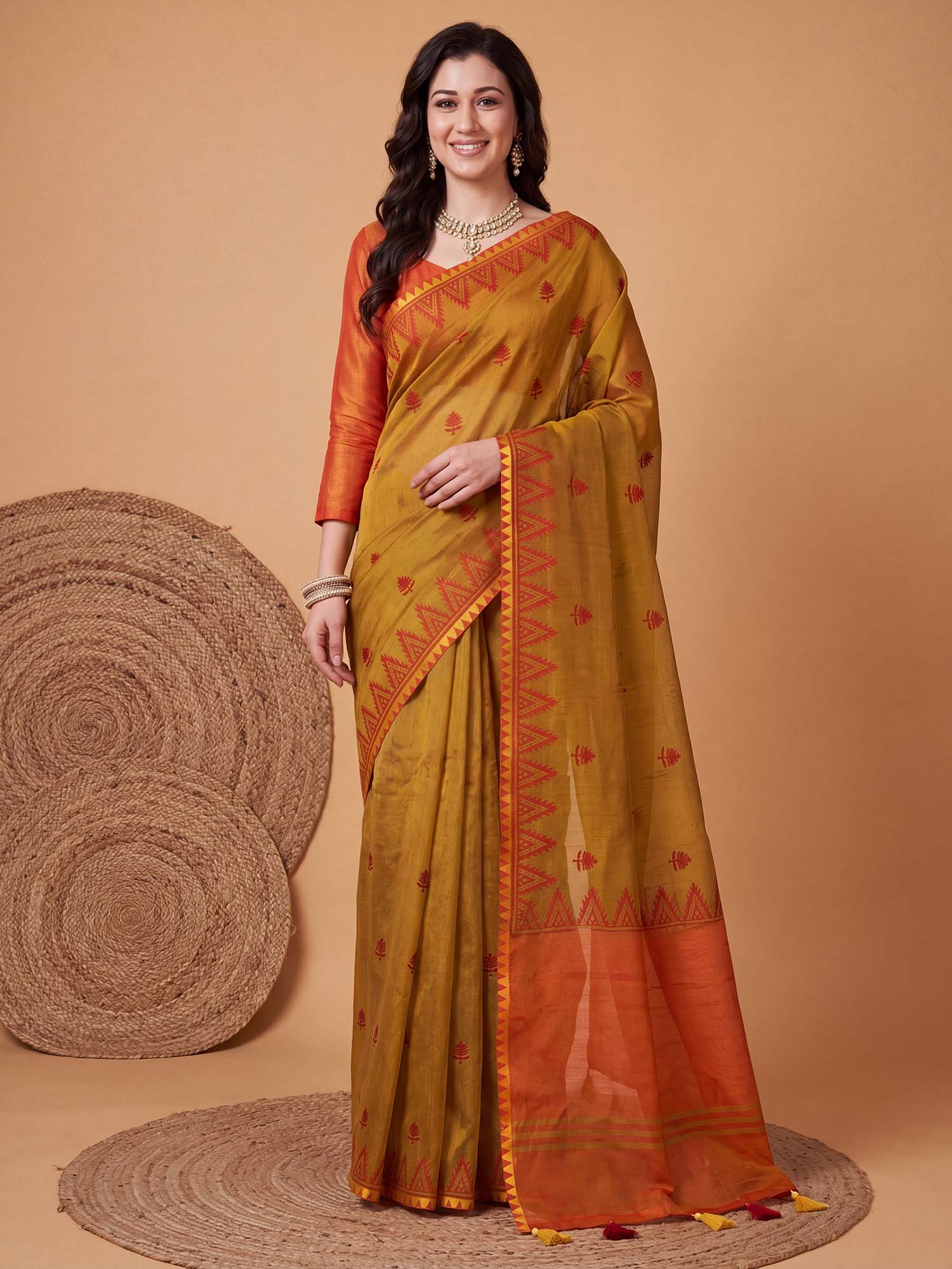Woman wearing gold linen saree with traditional indian motif work and orange blouse