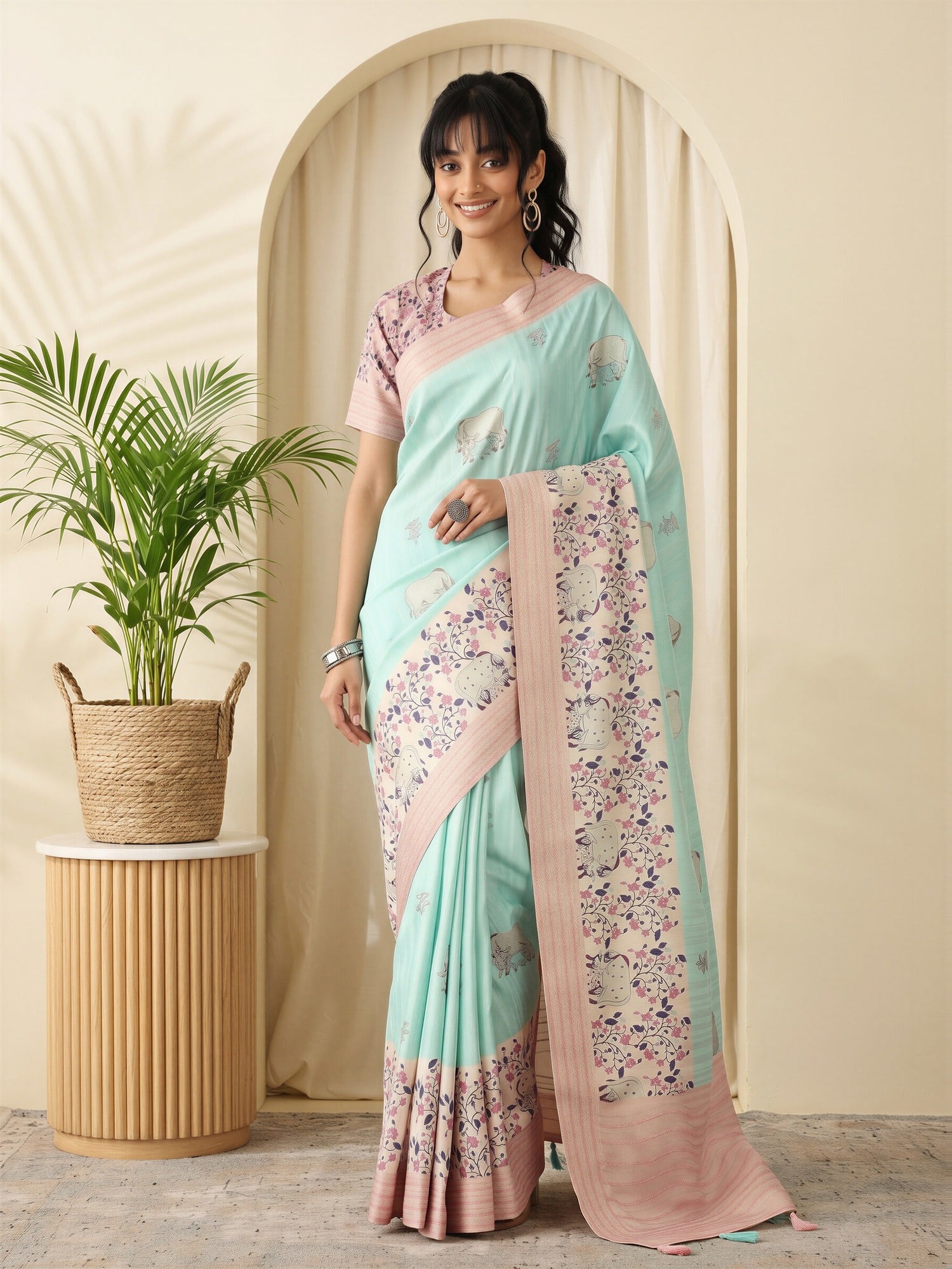 Woman wearing turquoise silk blend saree with traditional indian motif work and pink blouse