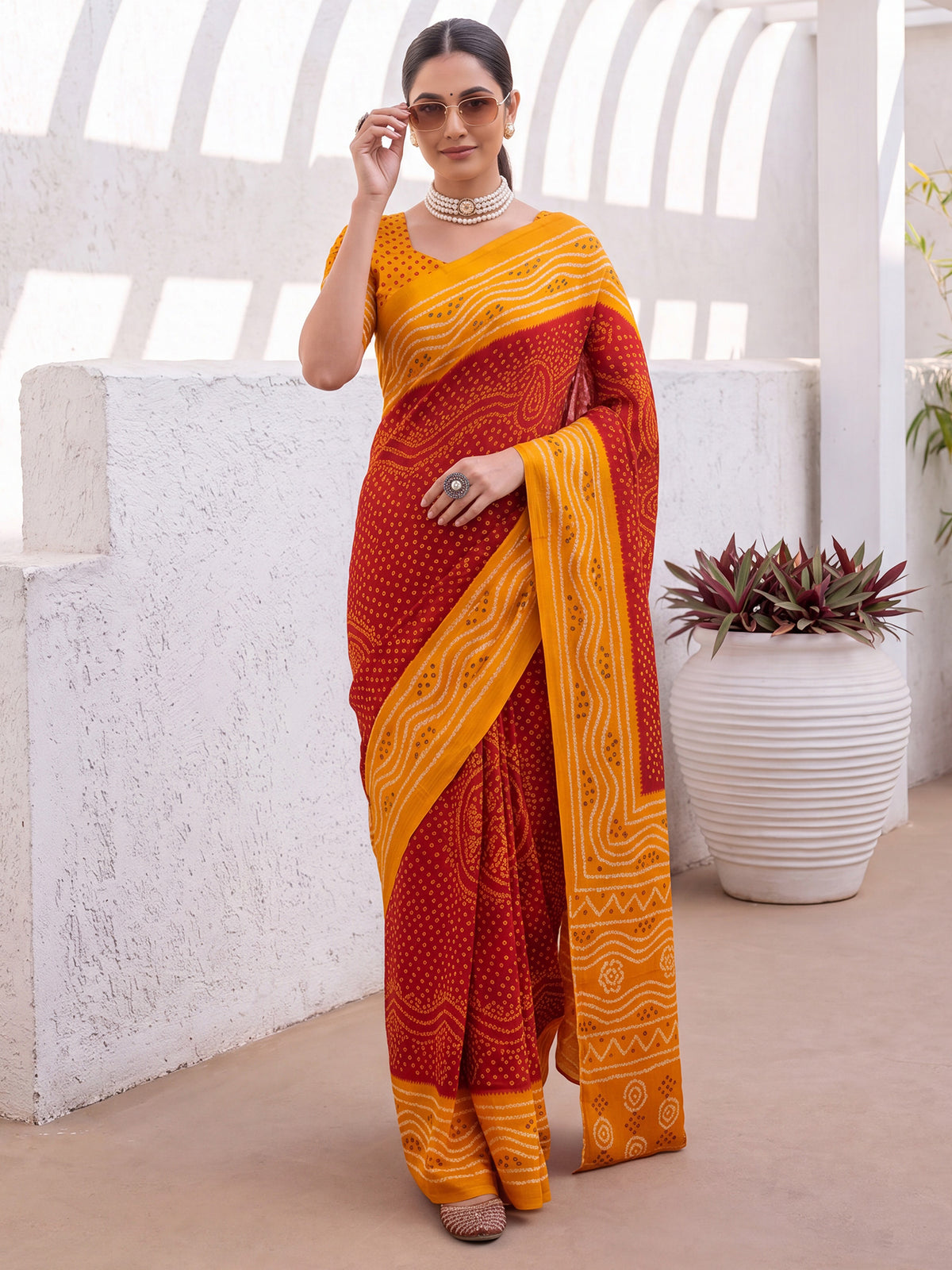 Woman wearing red satin silk saree with bandhani tie-dye dot work and orange blouse