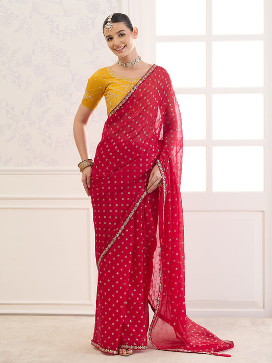Woman wearing red chiffon saree with metallic foil print work and yellow blouse