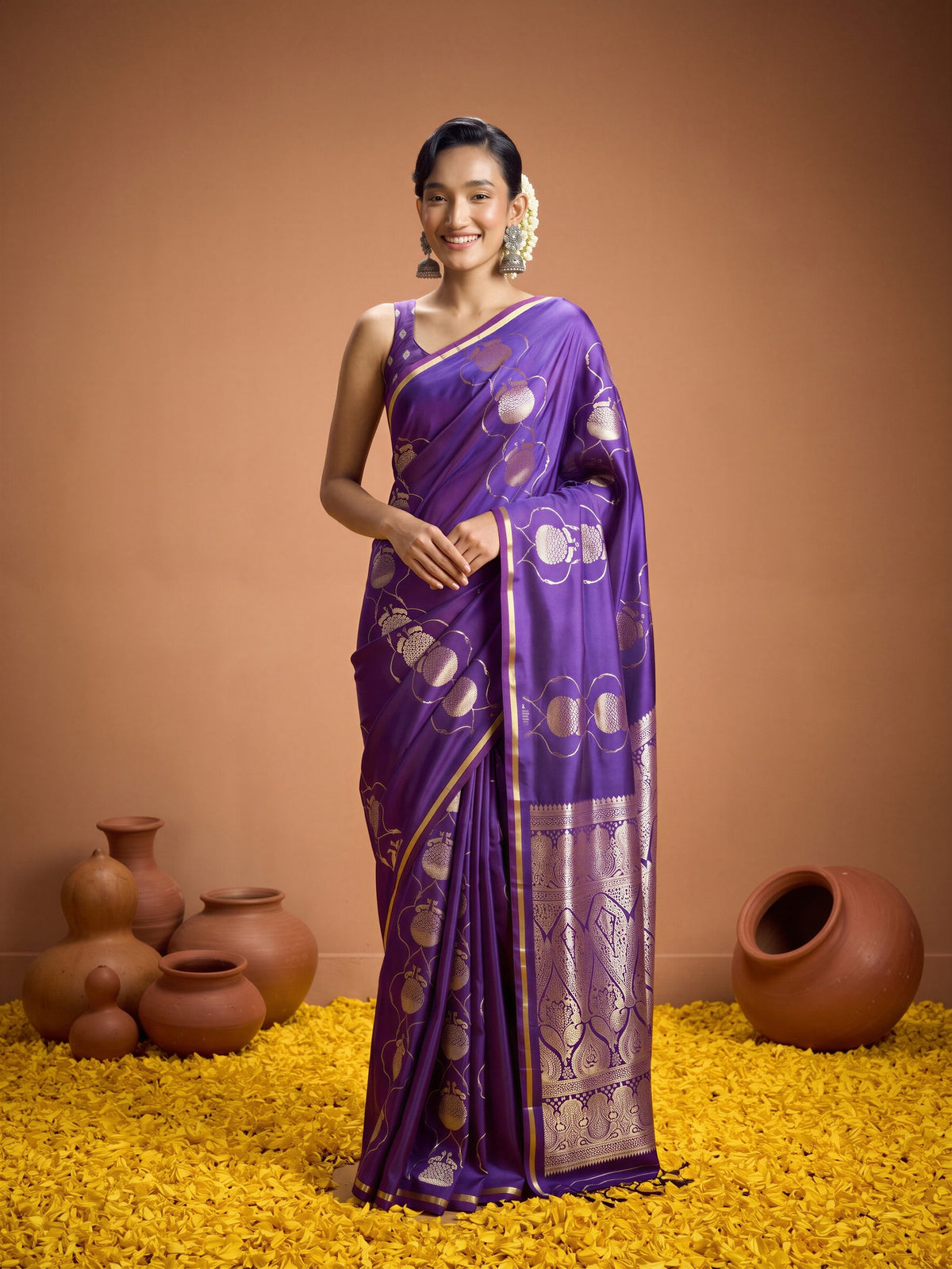 Woman wearing purple satin saree with zari butta (metallic motif) work and purple blouse