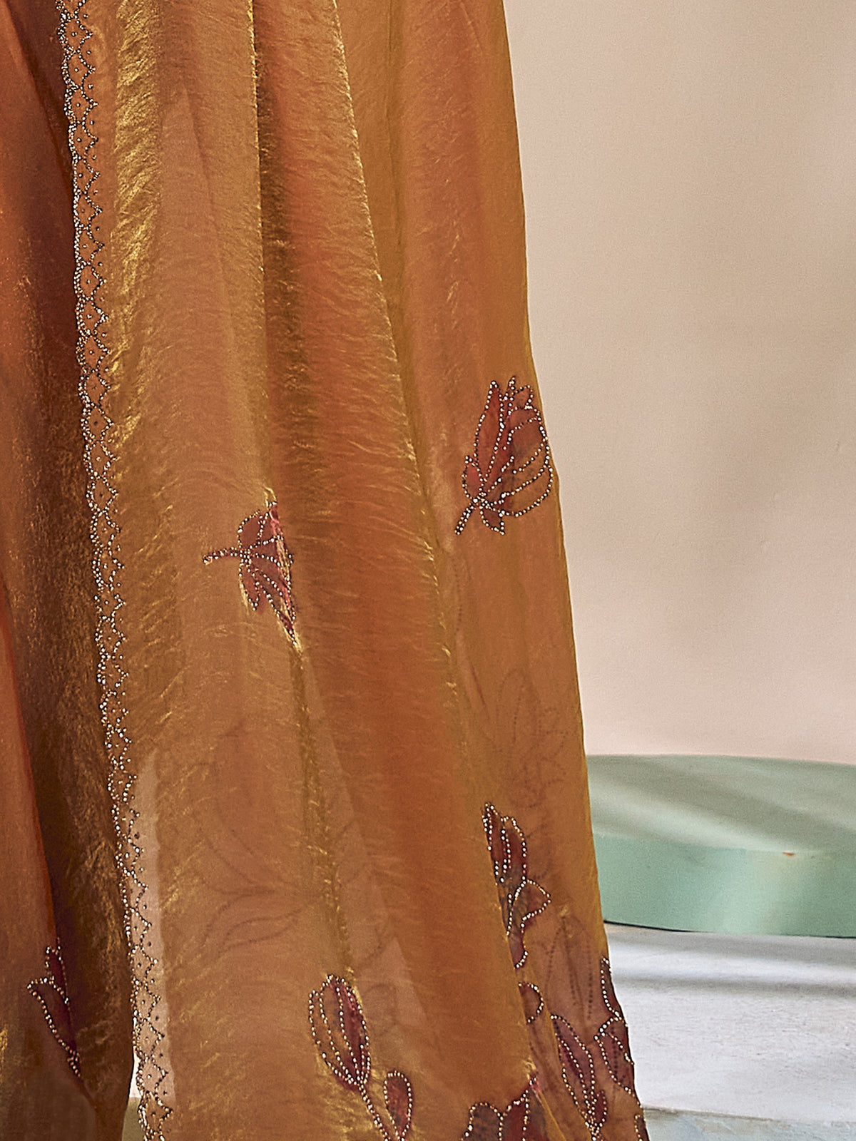 Pallu detail of bronze satin silk saree showing ornamented surface design and embellished border