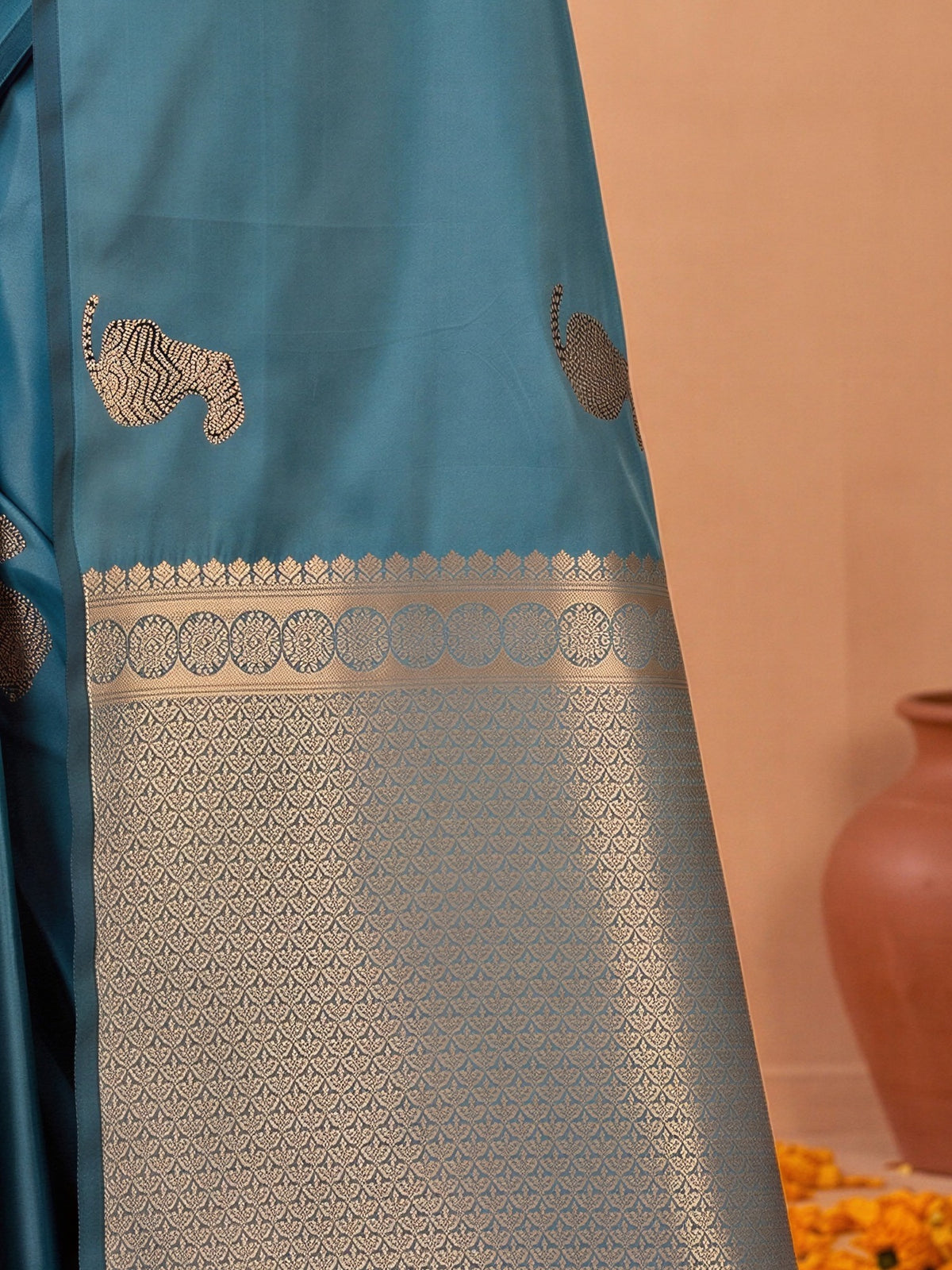 Pallu detail of teal blue satin silk saree showing animal-print design and no border border