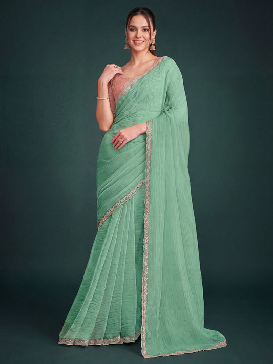 Woman wearing turquoise georgette saree with ornamented surface design and pink blouse