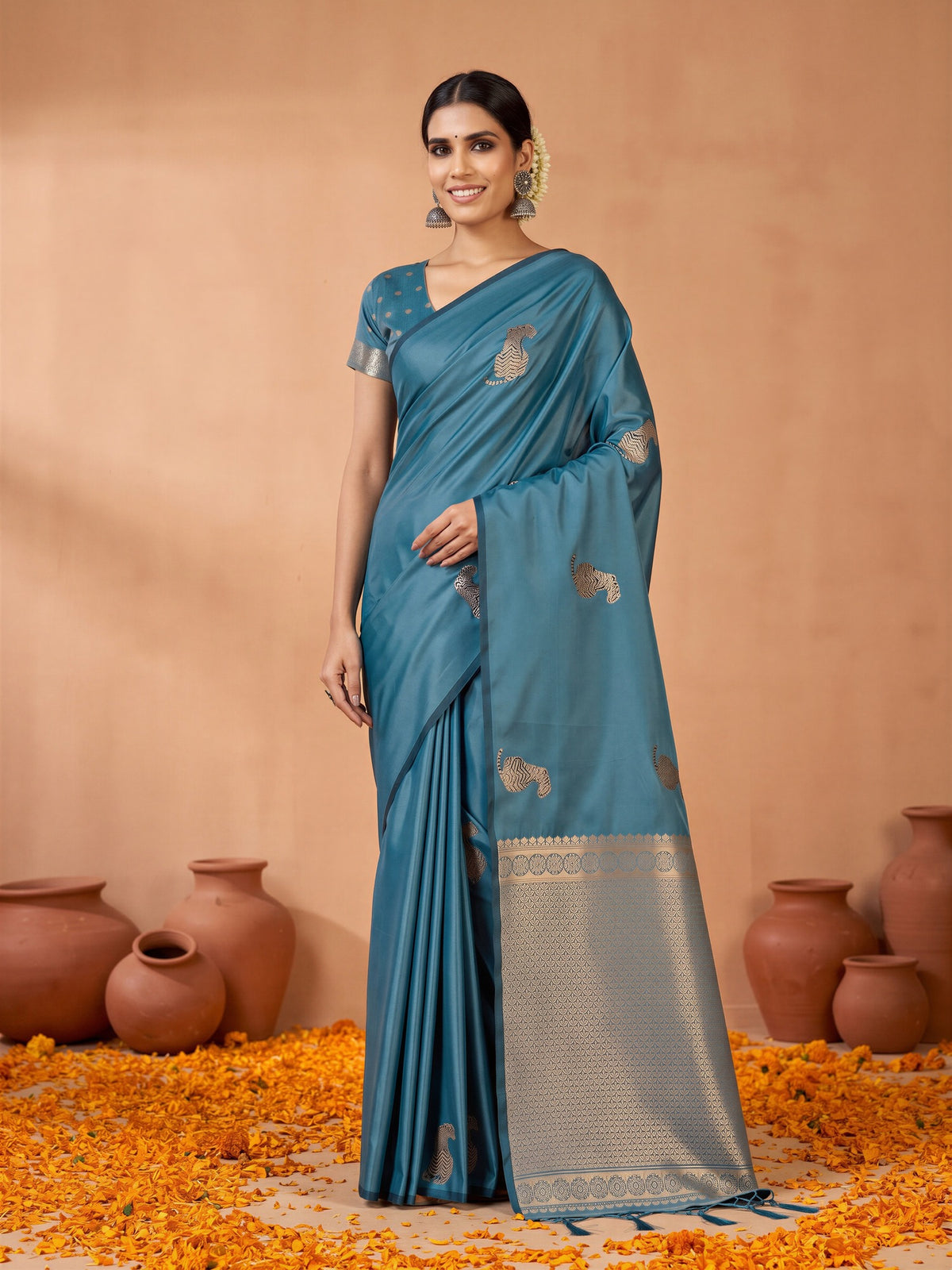 Woman wearing teal blue satin silk saree with animal-print design and teal blue blouse