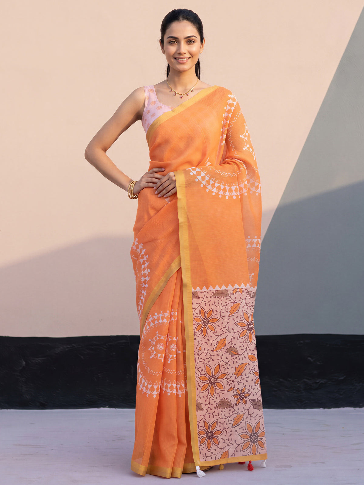 Woman wearing orange cotton blend saree with warli folk-art figures and pink blouse