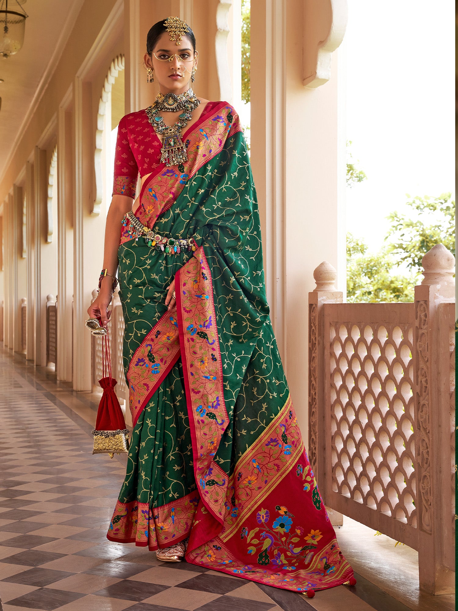 Woman wearing green silk blend saree with all-over floral design and red blouse