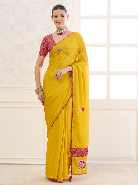 Woman wearing yellow chinnon saree with applique design and red blouse