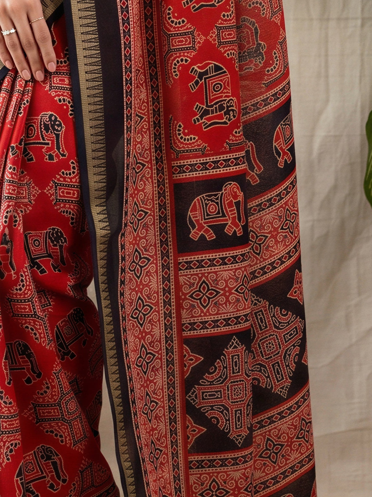 Pallu detail of rust georgette saree showing traditional indian motif work and zari border
