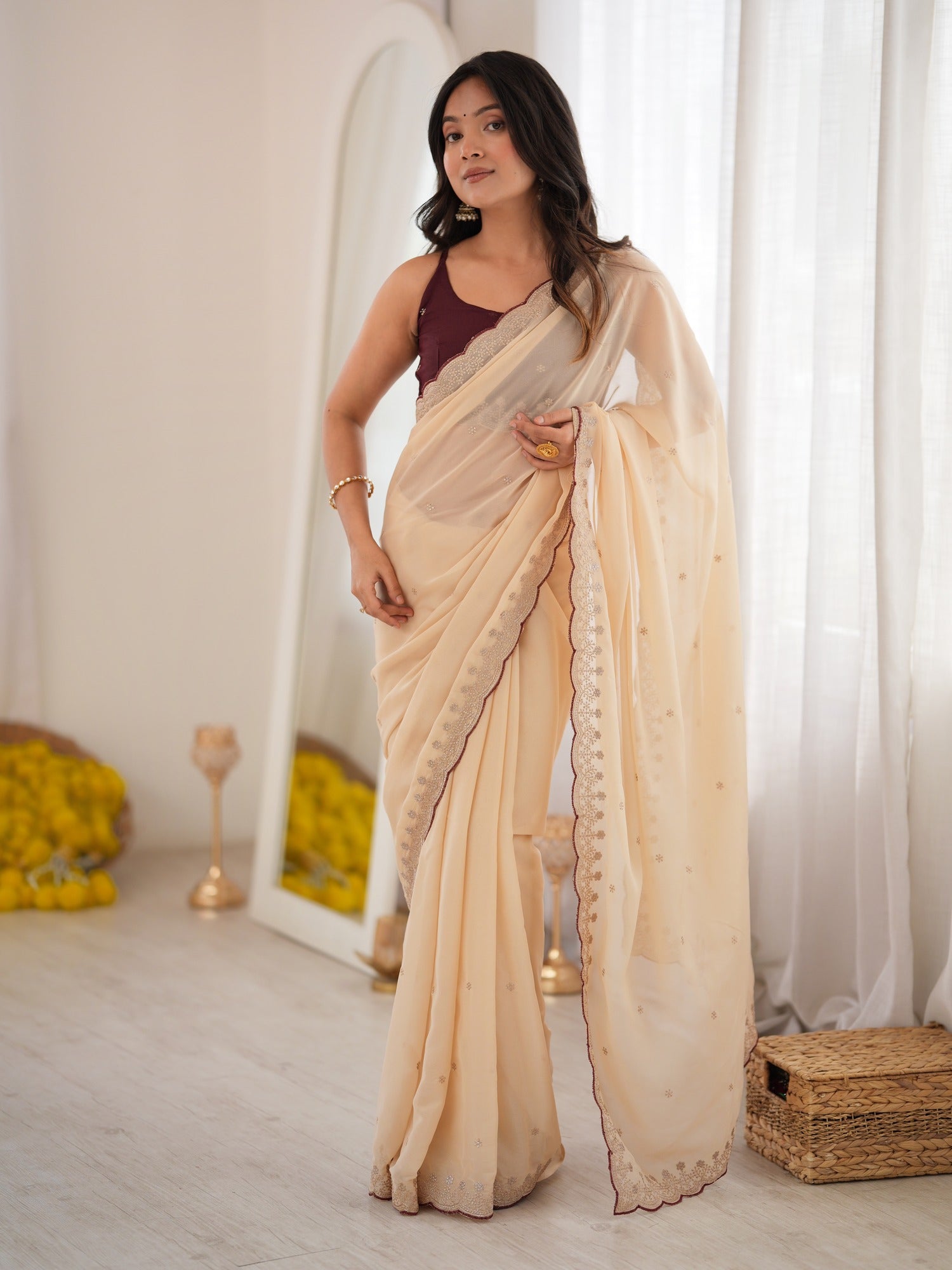 Woman wearing cream georgette saree with zari butta (metallic motif) work and brown blouse