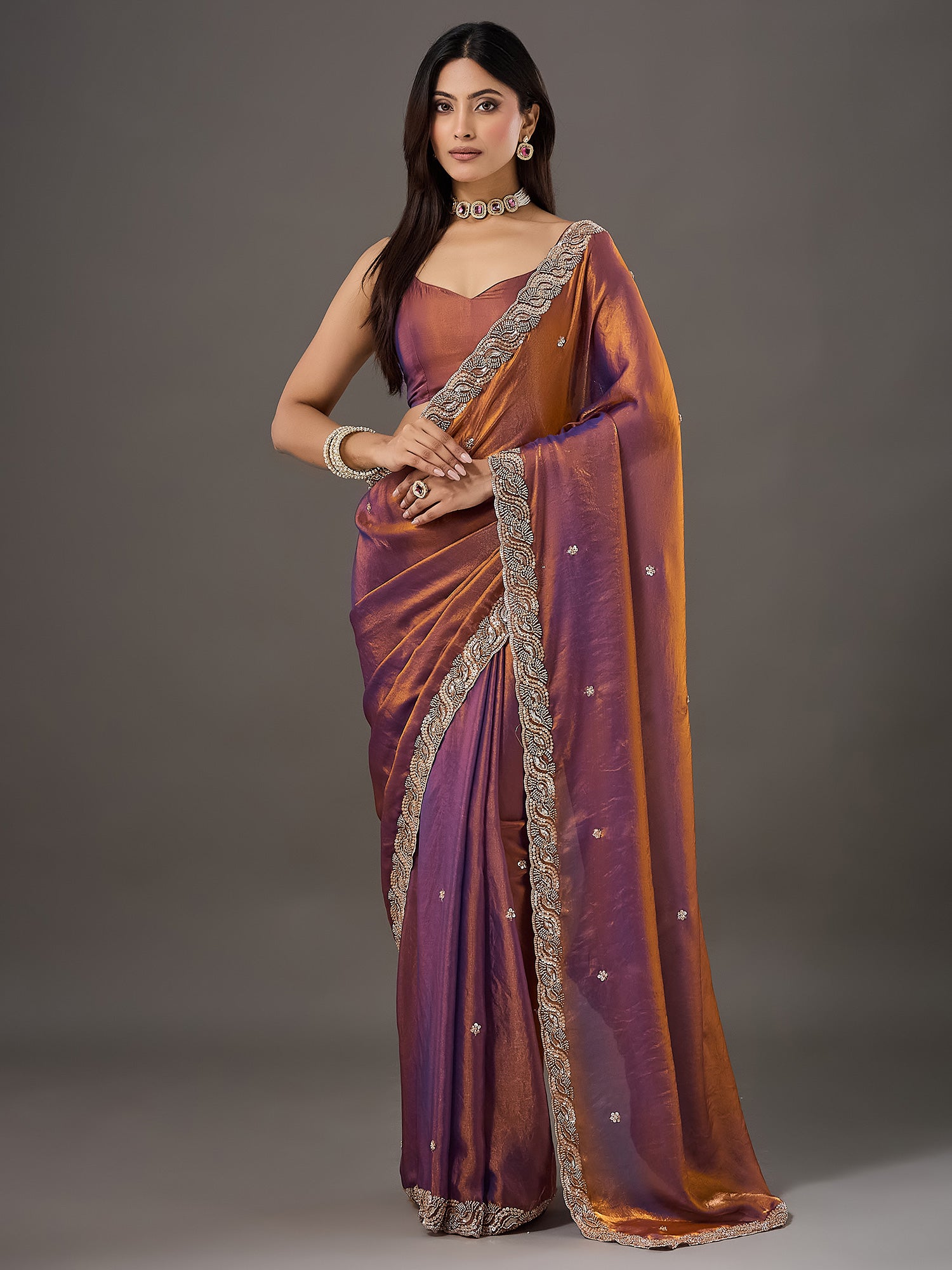 Woman wearing bronze satin saree with ornamented surface design and bronze blouse