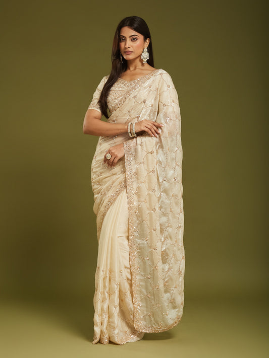 Woman wearing cream satin saree with ornamented surface design and cream blouse