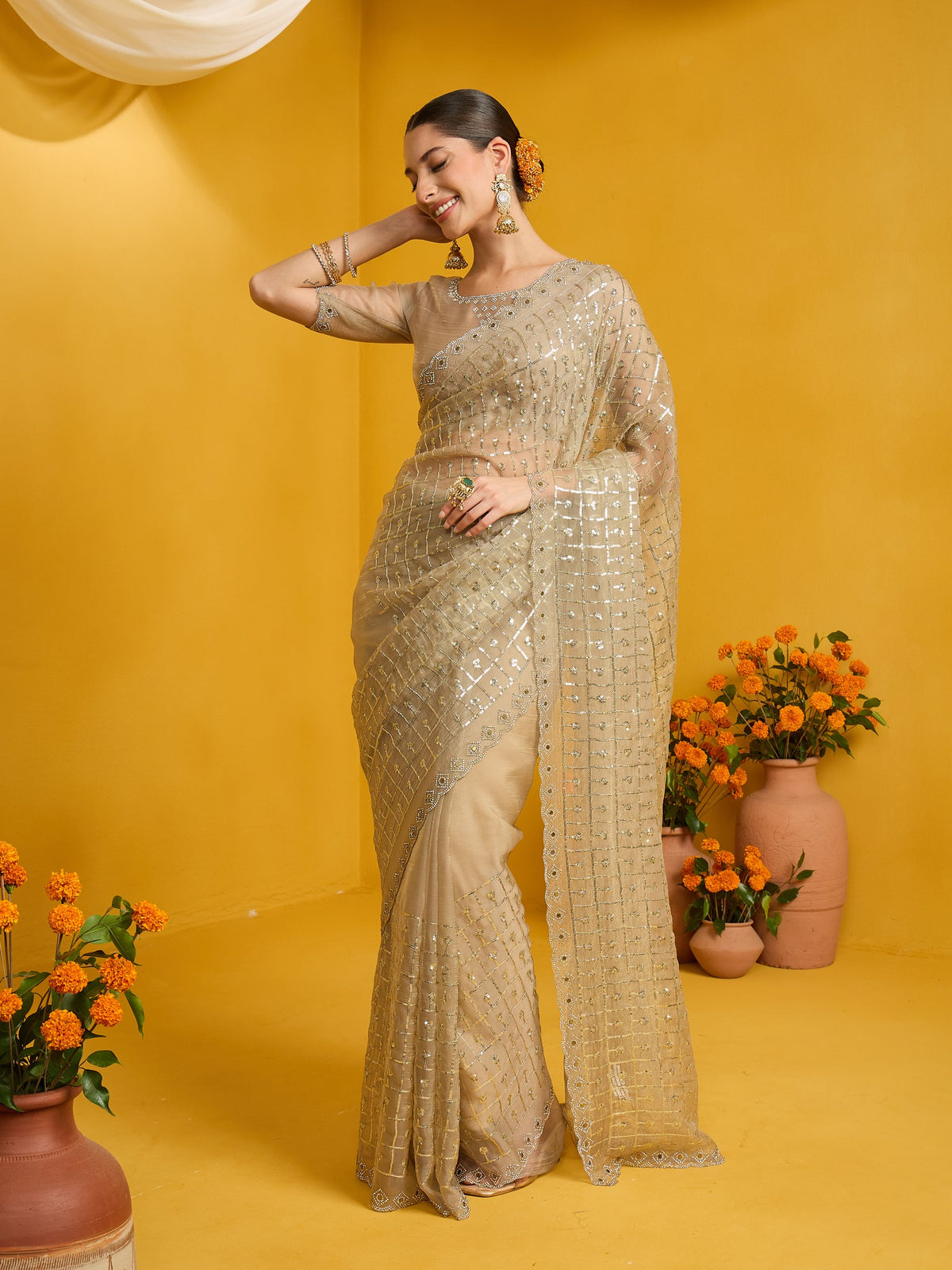 Woman wearing beige soft silk saree with ornamented surface design and beige blouse