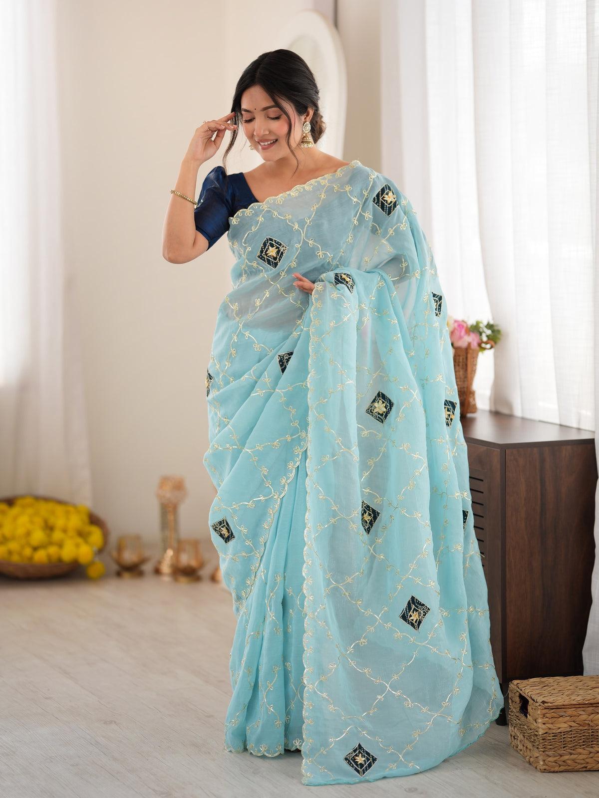 Woman wearing light blue paper silk saree with ornamented surface design and teal blue blouse