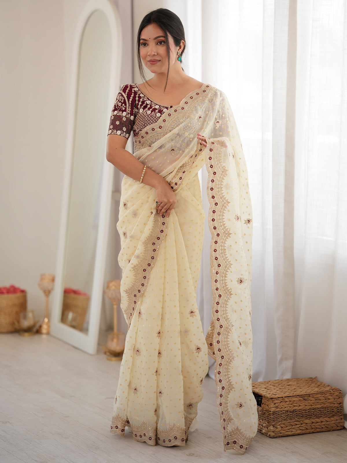 Woman wearing white silk blend saree with ornamented surface design and maroon blouse