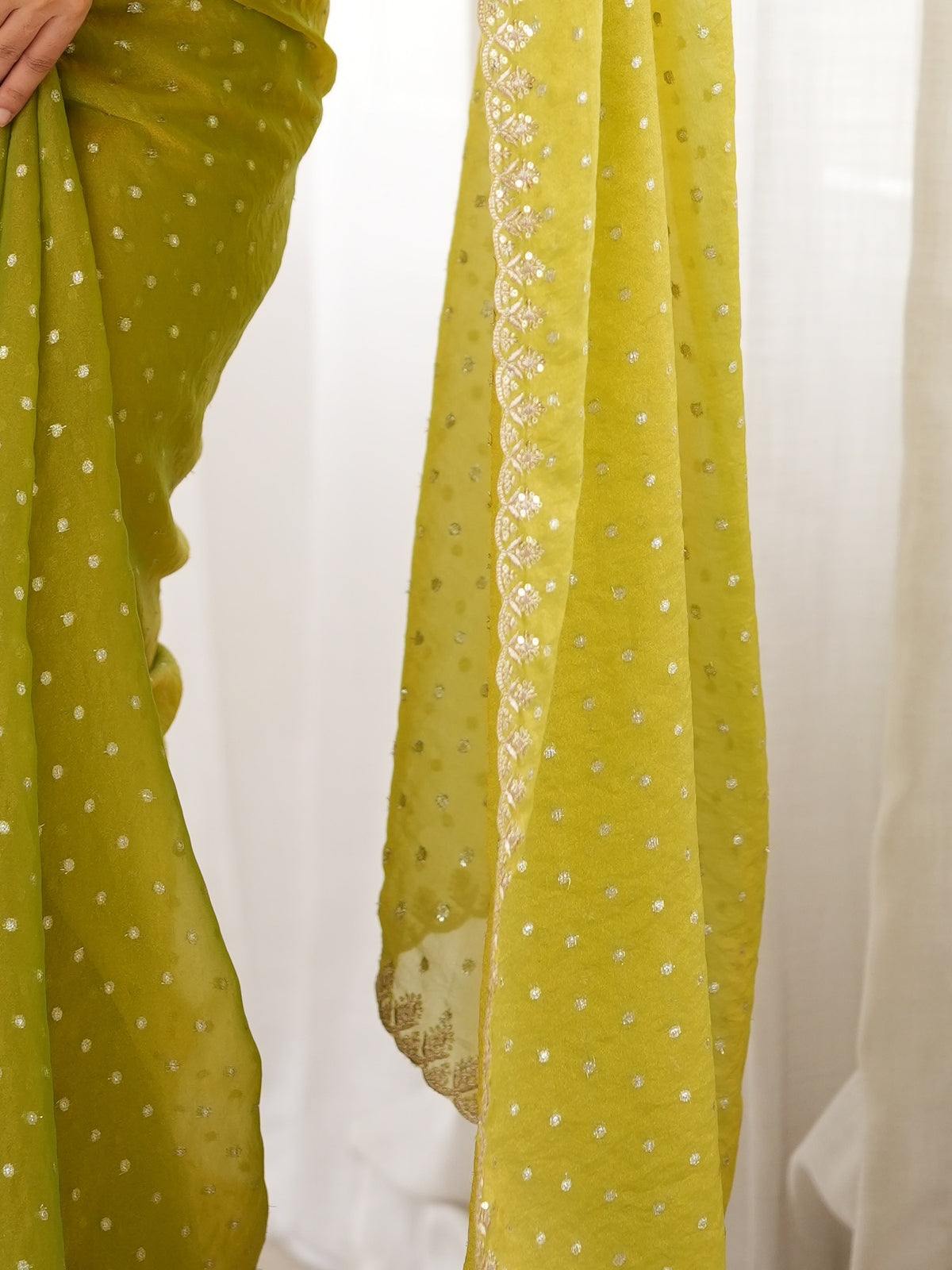 Pallu detail of lime green georgette saree showing zari butta (metallic motif) work and embellished border