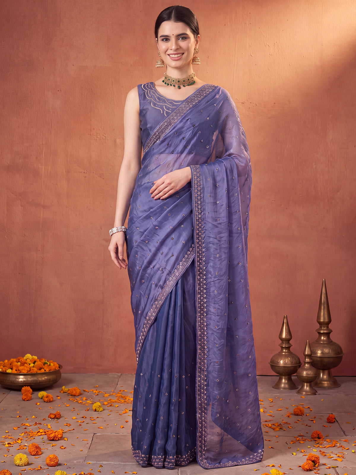 Woman wearing blue satin silk saree with ornamented surface design and blue blouse