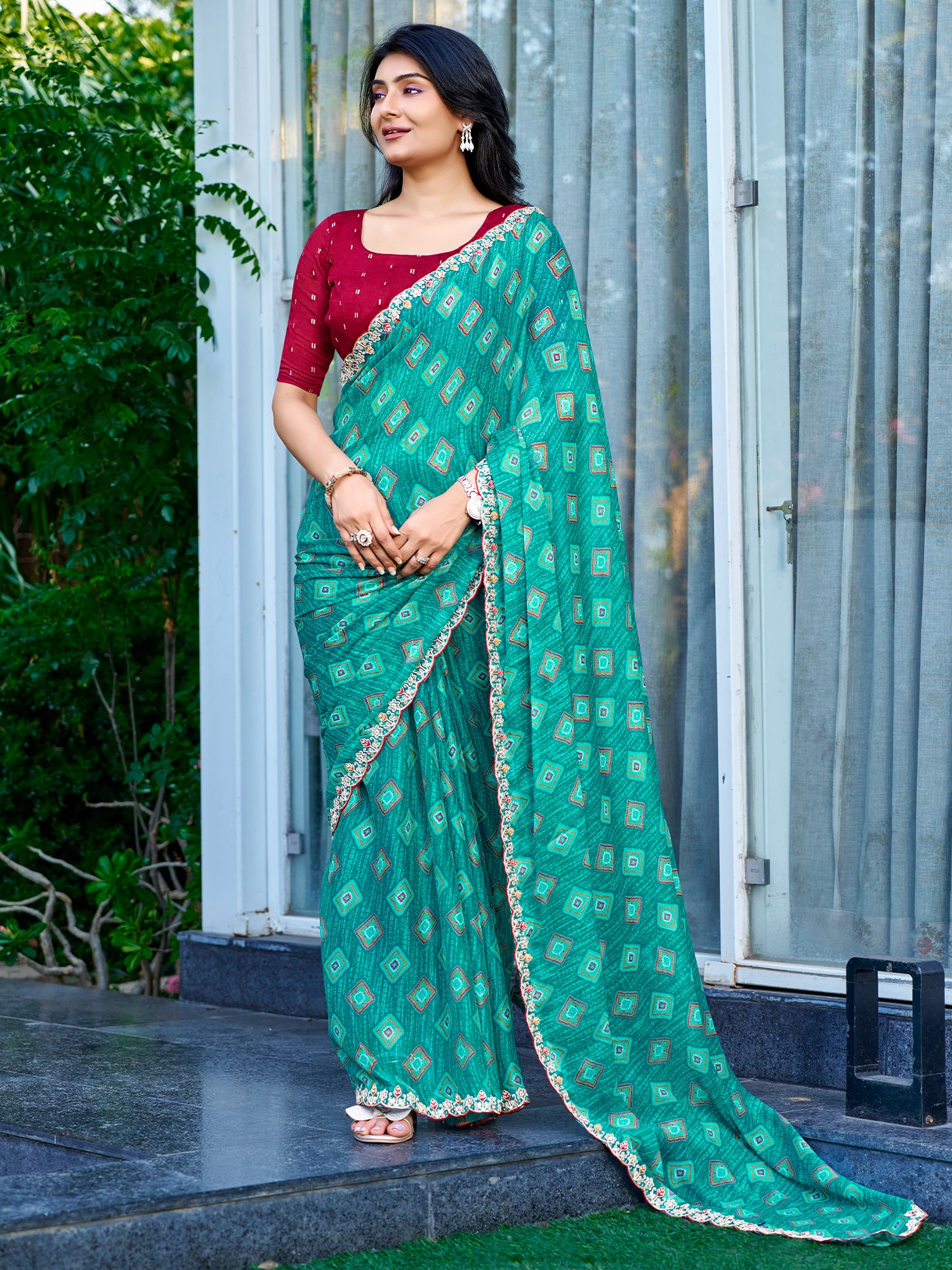 Woman wearing teal blue georgette saree with geometric pattern design and maroon blouse