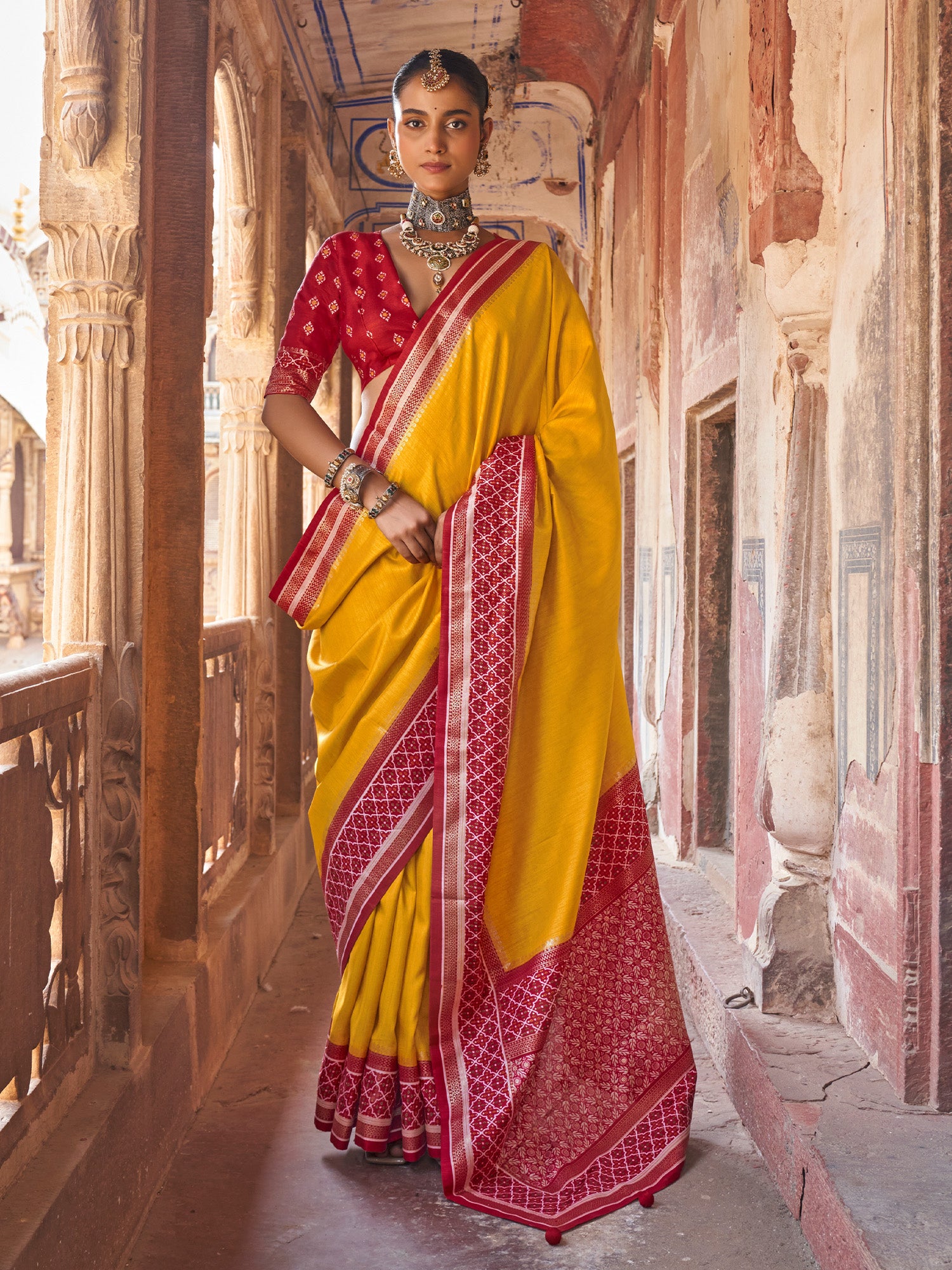 Woman wearing mustard silk blend saree with clean solid-tone finish and red blouse