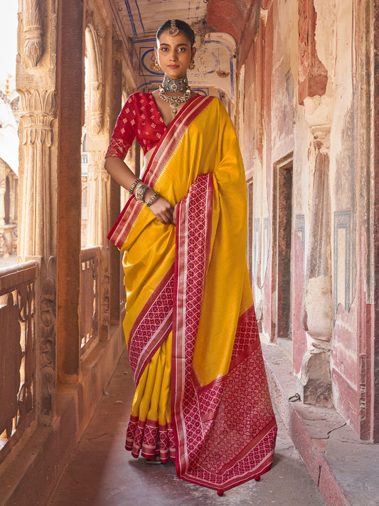 Woman wearing mustard silk blend saree with clean solid-tone finish and red blouse