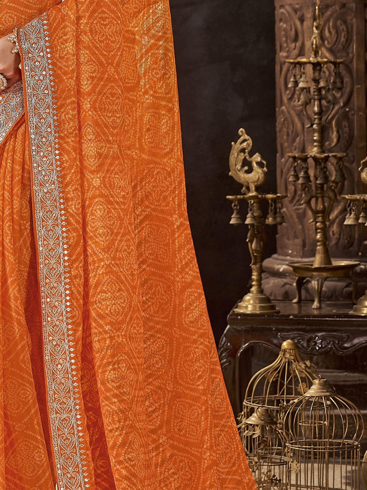 Pallu detail of orange chiffon saree showing bandhani tie-dye dot work and embellished border