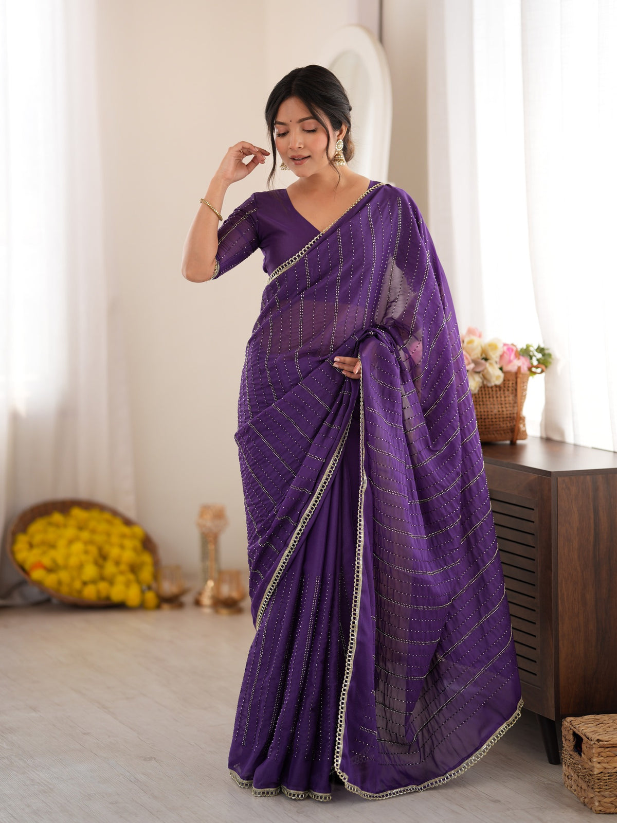 Woman wearing violet georgette saree with ornamented surface design and violet blouse