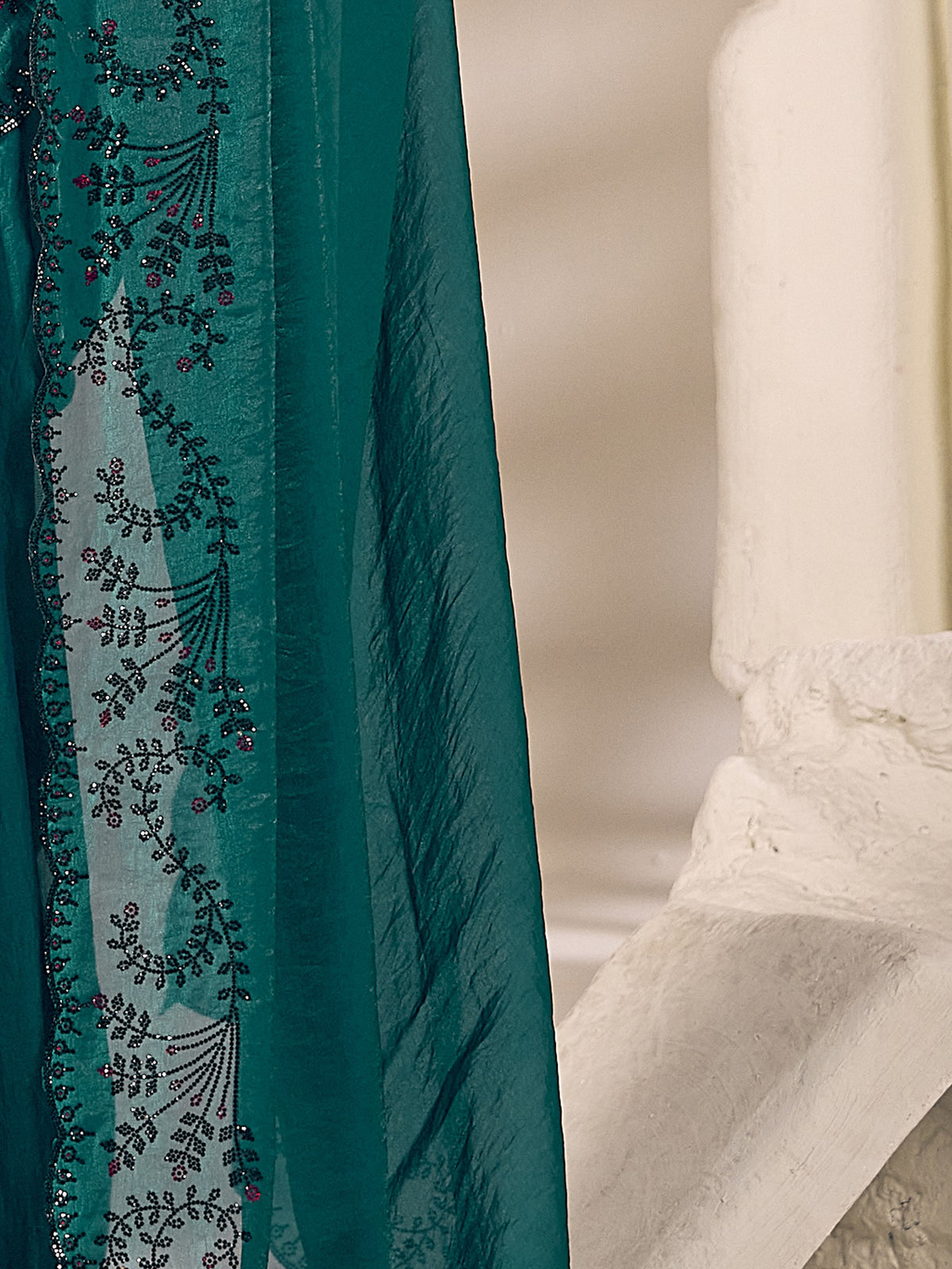 Pallu detail of teal green satin silk saree showing ornamented surface design and embellished border