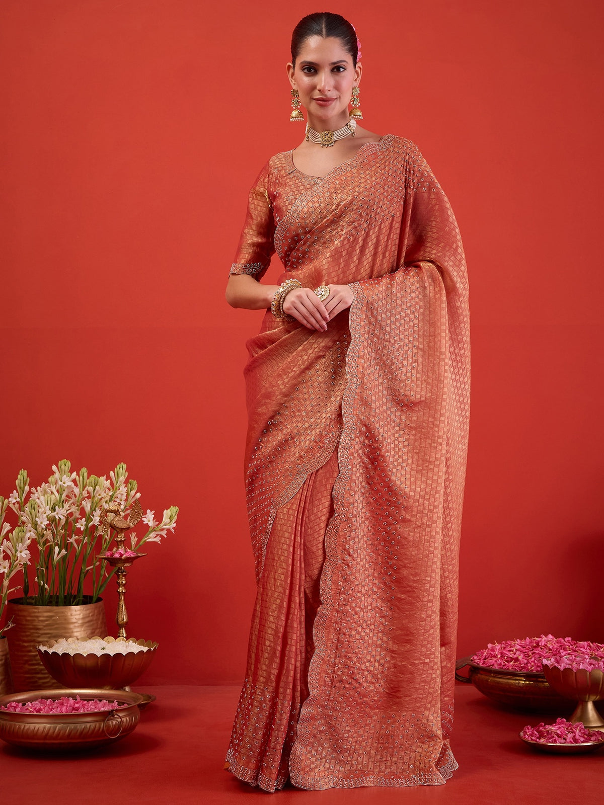 Woman wearing peach satin saree with ornamented surface design and peach blouse
