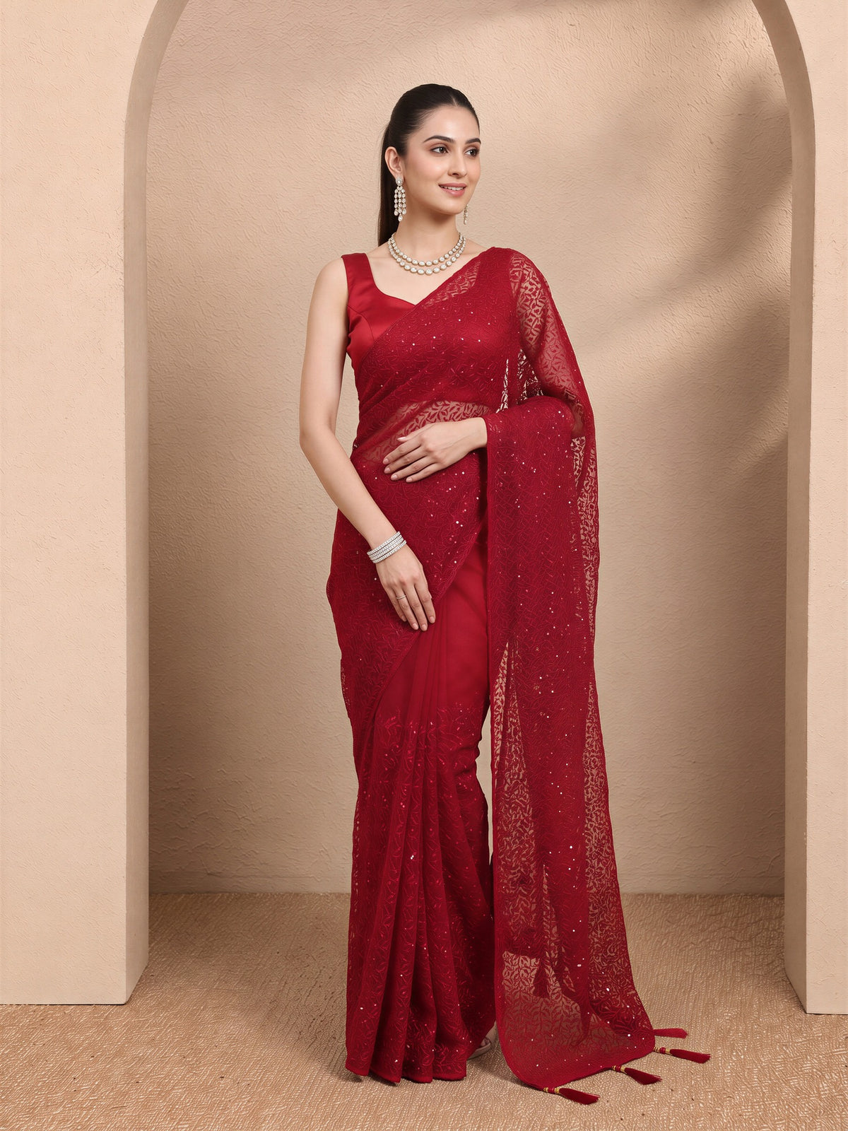 Woman wearing maroon net saree with embroidered motif work and maroon blouse