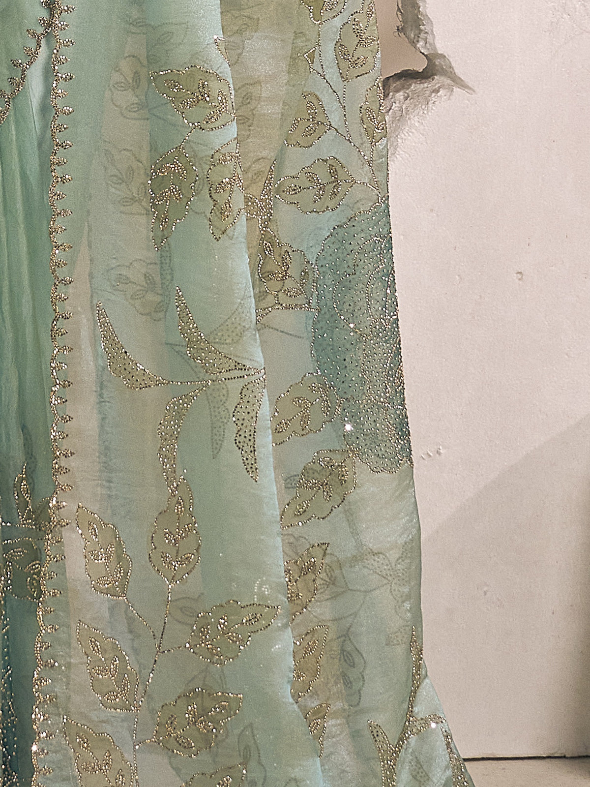 Pallu detail of light blue organza saree showing ornamented surface design and scallop border
