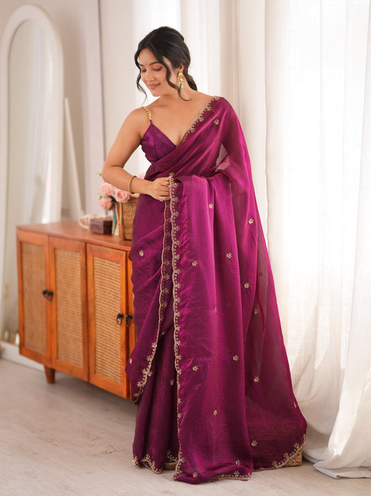 Woman wearing wine satin saree with ornamented surface design and wine blouse