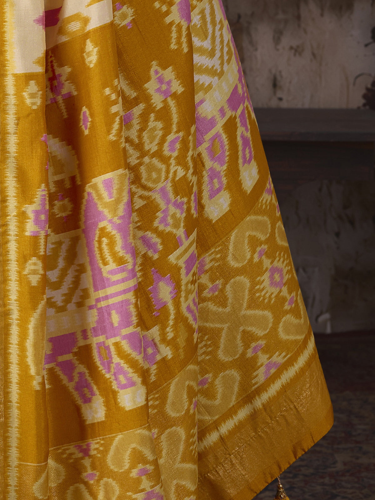 Pallu detail of off white silk blend saree showing ikat resist-dyed pattern and embellished border