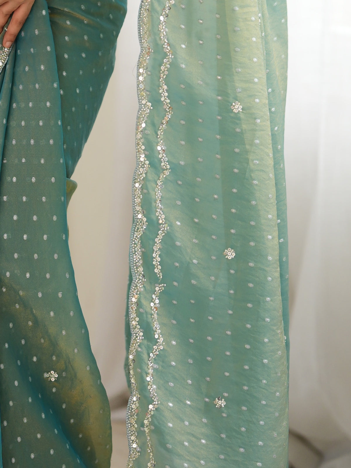 Pallu detail of light blue georgette saree showing zari butta (metallic motif) work and embellished border