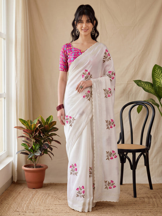 Woman wearing white vichitra silk saree with ornamented surface design and pink blouse
