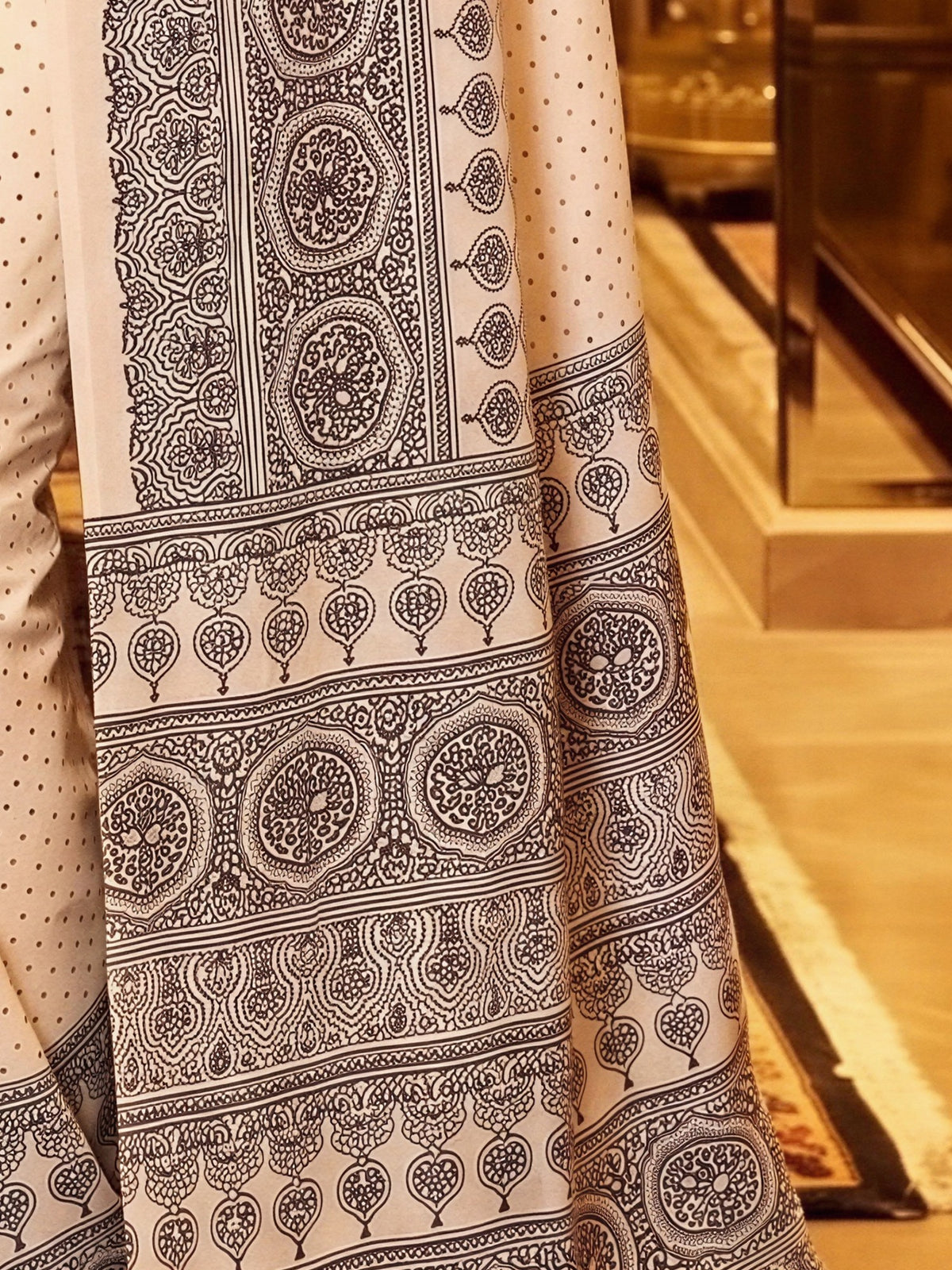 Pallu detail of cream satin saree showing ajrak block-print motif work and printed border