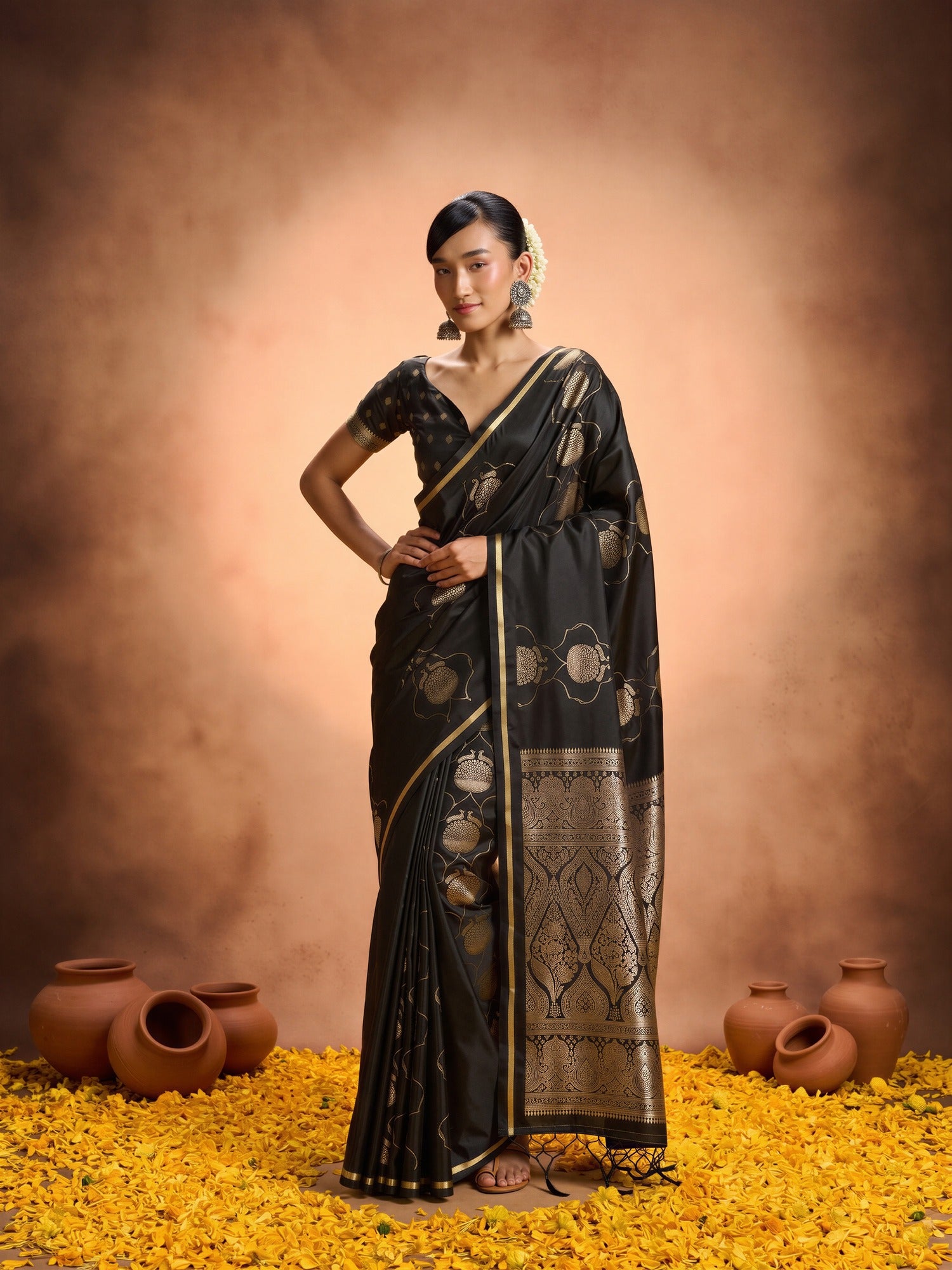 Woman wearing black satin saree with zari butta (metallic motif) work and black blouse
