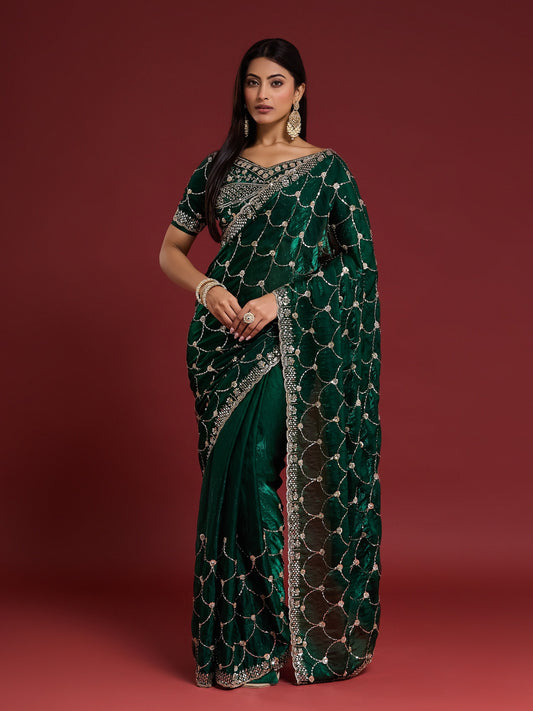 Woman wearing green satin saree with ornamented surface design and green blouse