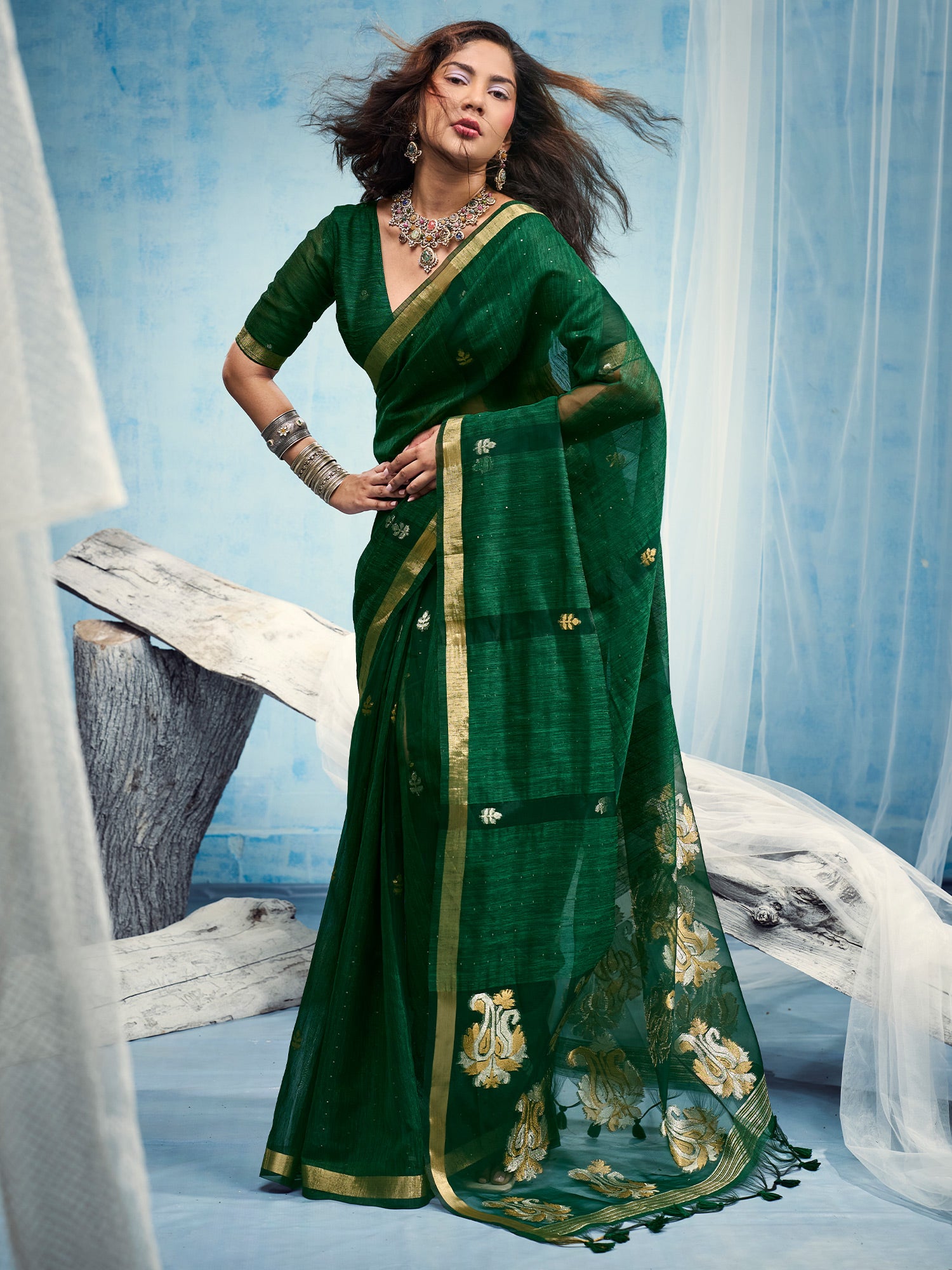 Woman wearing green muga silk saree with zari butta (metallic motif) work and green blouse