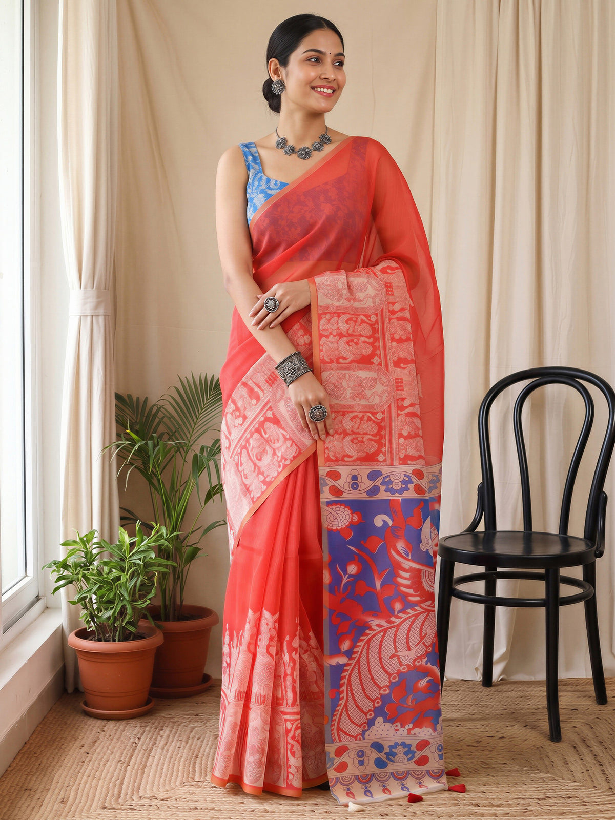 Woman wearing coral cotton blend saree with kalamkari narrative motif work and blue blouse