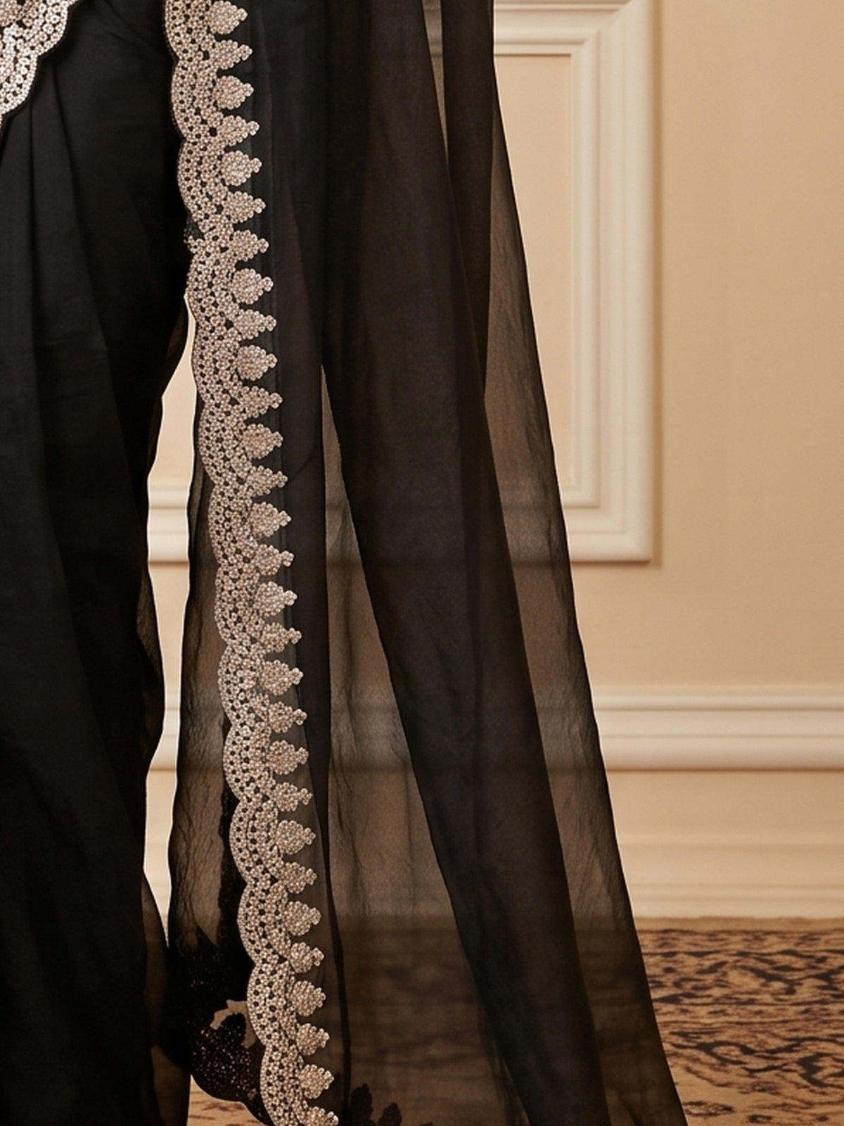 Pallu detail of black satin saree showing ornamented surface design and zari border