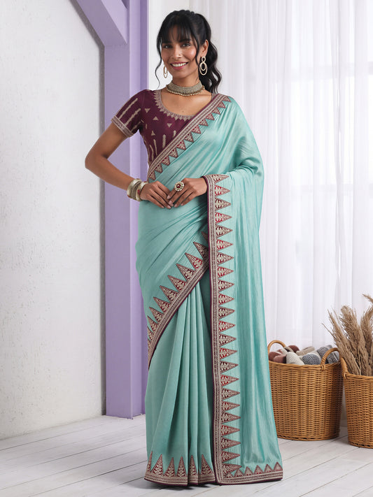 Woman wearing light blue vichitra silk saree with embroidered motif work and purple blouse