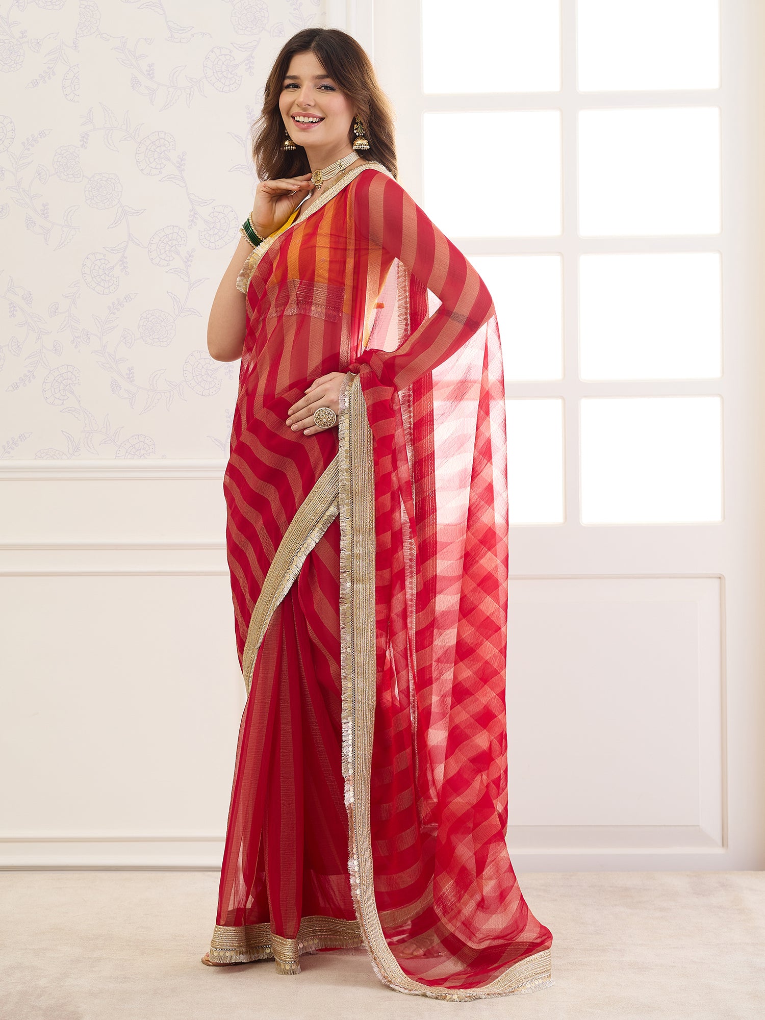 Woman wearing red viscose saree with striped pattern design and yellow blouse